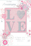 The anniversary card in this image presents a gentle, romantic scene, as if a whisper of an English spring garden has been captured on paper in the heart of Harlesden. At its centre, the word LOVE is formed in softly raised glitter, the sparkling surface rendered in blush tones with a distinctive silver-textured heart where the letter O would ordinarily be. This shimmering heart becomes the emotional focal point, glinting subtly like sunlight on petals in a quiet garden off Tubbs Road. Surrounding the central word, a halo of delicate blooms unfolds in hues of blush pink and muted mauve, the flowers illustrated with an almost watercolour softness. Fine lines and flowing curves trace petals, stems, and leaves, giving a feeling of movement and care, as if each flourish were sketched by a florist envisioning an anniversary bouquet for delivery around Harlesden and Neasden. Tiny details-swirling tendrils, scattered petals, and the faintest outlines of butterflies-add a touch of whimsy without disturbing the card's calm harmony. The background remains a soft pastel pink, gently graded so that the central motif appears to glow. Above and below the floral design, elegantly understated script spells out On Our Anniversary and I love you today and always, the lettering slender and poised, expressing affection without excess. Overall, the composition conveys an intimate, cherished mood: a keepsake card that feels like a companion to a vase of fresh roses or lilies on an anniversary table, capturing the tenderness, shared journey, and deeply personal romance that couples across Harlesden celebrate year after year.